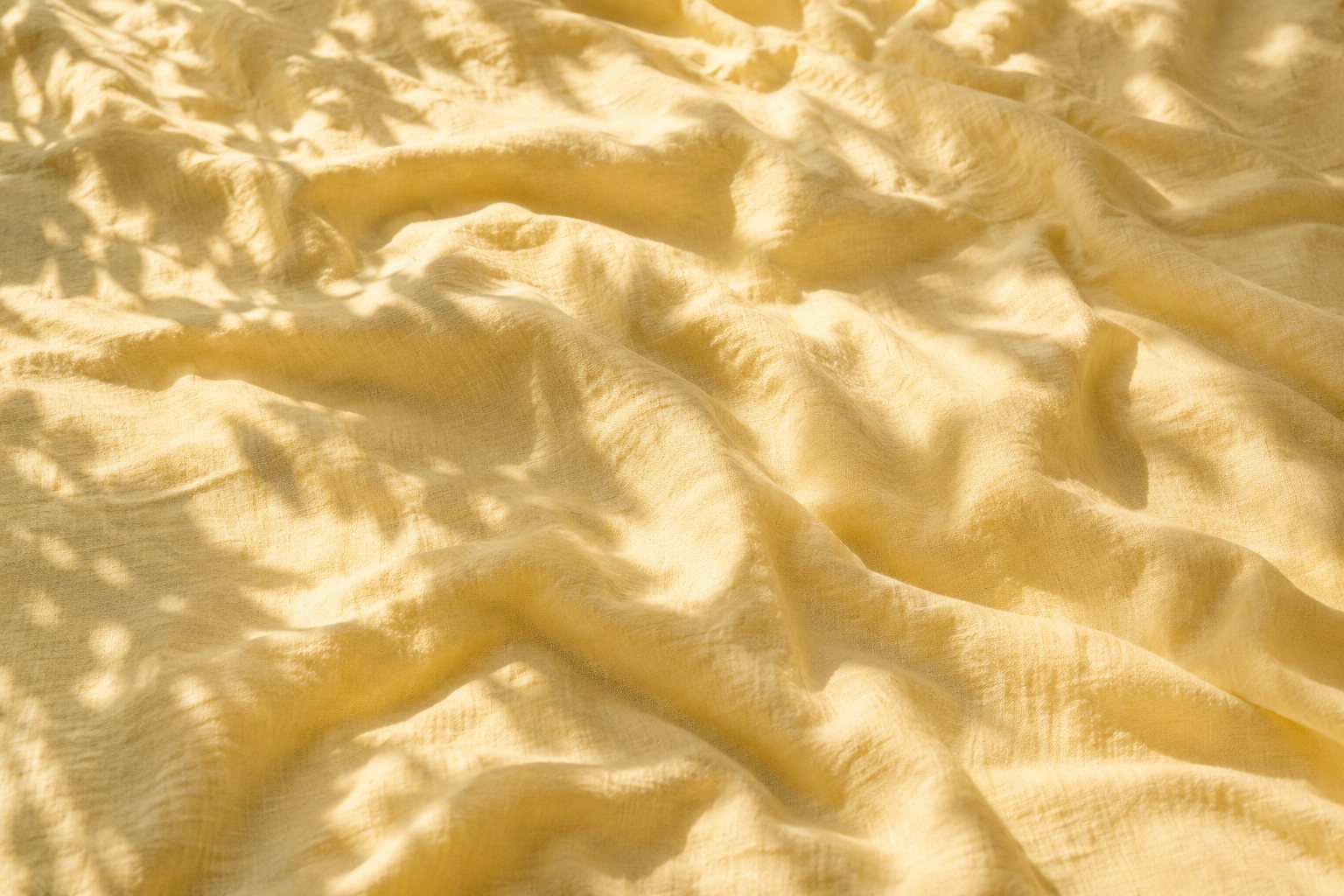 Sunlit butter yellow linen with soft leaf shadows